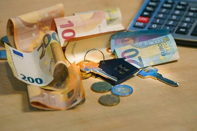Notas de euro, chaves de casa e calculadora para calcular os impostos e mais-valias na venda de casa
