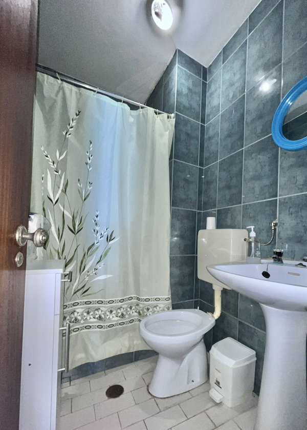 Casa de banho com azulejos azuis, base de duche com cortina e lavatório de coluna, apartamento T3 em Portimão