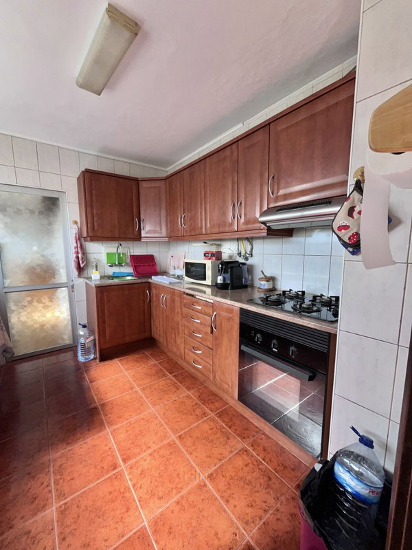 Cozinha com armários de madeira, placa de gás e forno embutido, apartamento T3 em Portimão